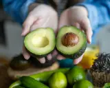Hände halten eine aufgeschnittene Avocado. Tipps für avocado haltbar machen.