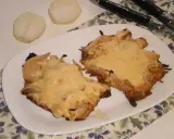 Pyszny schab w cebuli, zapieczony z serem, idealny na niedzielny obiad. Obok leżą połówki cebuli.
