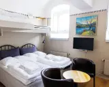 Ett mysigt rum på Langholmen Hotel med våningssängar, dubbelsäng, konst och TV.