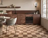 Cucina moderna con pavimento a scacchiera che crea una **tabella colori caldi**. Mobili marroni, tavolo rotondo e sedie grigie.