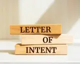 Drewniane klocki z napisem "LETTER OF INTENT" tworzą symboliczny list intencyjny, zapowiadający przyszłe działania.