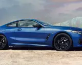 Błękitne BMW 840i z czarnymi felgami na tle pustynnego krajobrazu i gór.