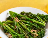 Bimi zubereiten in der Pfanne: Grüner Spargel mit knusprigen Röschen, leicht gebräunt und mit einer würzigen Kruste bestreut, auf einem weißen Teller.