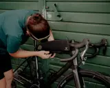 Osoba montuje torbę podsiodłową do roweru. Przygotowania do składania roweru przed wyprawą.