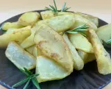 Patatas gajo doradas y crujientes, adornadas con ramitas de romero fresco, servidas en un plato oscuro.
