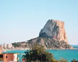 Widok na majestatyczną skałę Peñón de Ifach, symbol Costa Blanca atrakcje. Turkusowe morze i zabudowania miasta tworzą malowniczy krajobraz.