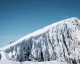 En grupp skidåkare på en helags topptur, med en dramatisk snöklädd bergssida och klarblå himmel.