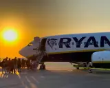 Pasażerowie wsiadają do samolotu Ryanair na tle zachodzącego słońca.