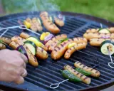 Grillad korv med grönsaker på en het grill. Röken stiger och doften sprider sig.