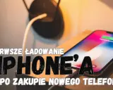 Pierwsze ładowanie iPhone'a po zakupie. Na ekranie widać ikonę baterii, a obok leży ładowarka.