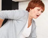 Kobieta z bólem w dolnej części pleców, zastanawia się, czy to korzonki czy nerki.