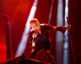Dave Gahan sjunger passionerat under en Depeche Mode konsert, badad i rött ljus.