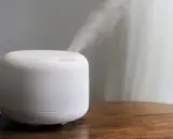 Humidificador casero blanco emitiendo vapor sobre una mesa de madera.