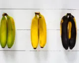 Drei Paare Bananen zeigen verschiedene Stadien der Reife: grün, gelb und überreif. So kann man sehen, wie Bananen lagern.