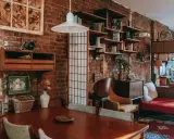 Wnętrze kawalerki z ceglaną ścianą, drewnianym stołem i meblami w stylu vintage.