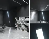 Nowoczesne wnętrze z listwą LED natynkową na suficie i ścianie. Minimalistyczny design, biurko, krzesło i regał z książkami.