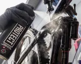 Rękawica z puszką "PROTECT" rozpyla środek na ramę roweru elektrycznego, pokazując, jak myć rower elektryczny.