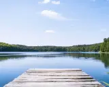 Holzsteg am ruhigen See, umgeben von grünen Wäldern. Ein perfekter Ort für einen geheimtipp mecklenburgische seenplatte Urlaub.