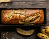 Un delizioso banana bread light appena sfornato, con banane caramellate in superficie, su un tagliere di legno.