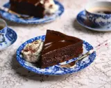 En bit chokladkaka med glansig ganache och vispgrädde, serverad med kaffe. Perfekt för ett enkelt ganache recept.