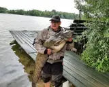 Wędkarz z okazałym sumem na brzegu jeziora Długie koło Szczytna.