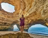 Frau steht in Höhle, blickt auf Meer. Ein Highlight der Algarve.