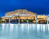 Elegancki Starlight Resort Hotel nocą, z oświetlonym basenem i palmami.