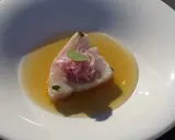 Bonito fresco en un caldo dorado, coronado con cebolla morada y una hoja verde. Un plato ligero y sabroso.