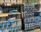 Scaffali pieni di bottiglie d'acqua in pacchi multipli. Il prezzo di 73 centesimi per una bottiglia d'acqua in crociera è un affare!