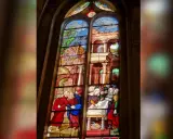 Magnifique **verre d'église** racontant des scènes bibliques, avec des personnages en habits d'époque et des paysages stylisés.