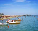Spiaggia affollata a Gabicce, con ombrelloni colorati, gente in acqua e pedalò. Un'estate vivace al banana beach Gabicce.