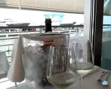 Un bicchiere di vino bianco e una bottiglia in un secchiello di ghiaccio, con vista sul porto e yacht, al ristorante club nautico Rimini.