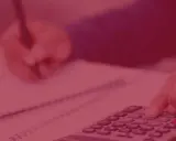 Ręka naciska klawisze kalkulatora, druga pisze w notatniku. To obrazek dla tych, którzy chcą wiedzieć, jak zostać kontrolerem finansowym.