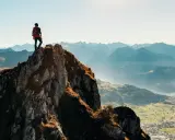 Turysta na szczycie góry, podziwiający panoramę. Ile się idzie na Rysy? To zależy od kondycji i wybranej trasy, ale widok wynagradza wysiłek.