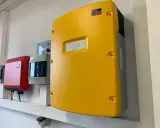 Gul SMA solcellsväxelriktare, en röd enhet och en grå enhet monterade på en vägg. En solig dag för att maximera din sunny tripower.