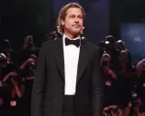 Brad Pitt looking dapper in a classic tuxedo with a black cummerbund and bow tie, posing for photographers.