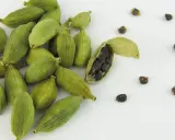 Gousses de cardamome verte, dont une ouverte révélant ses graines noires. Découvrez les cardamome bienfaits pour la santé et la cuisine.