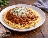 Pyszne spaghetti bolognese, idealne na prosty obiad. Makaron z bogatym sosem mięsnym, posypany parmezanem i natką pietruszki.