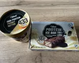 Gdzie kupić lody proteinowe? Na zdjęciu widać opakowania lodów Gelatelli: kubełek masło orzechowe i batoniki ciasteczkowe.
