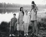 Czarno białe zdjęcie. Rodzina na tle jeziora. Ojciec niesie córkę na barana, obok mama i dwaj synowie.