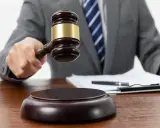 Sędzia trzyma młotek, symbolizując proces. Zastanawiasz się, ile trwa upadłość konsumencka bez majątku?