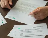 Dłonie przeglądają dokumenty ZUS. Czy to czas na emeryturę, kiedy przejść?