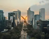 Goldene Viktoria-Statue im Sonnenuntergang, umgeben von modernen Wolkenkratzern in Mexico City.