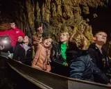 Rodzina płynie łodzią przez sztolnię czarnego pstrąga, podziwiając skalne ściany i światło.