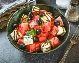 Erfrischender Melonen Feta Salat mit schwarzen Oliven und Minze, beträufelt mit Balsamico-Dressing. Perfekt für heiße Tage!
