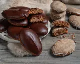 Biscotti tipici calabresi, alcuni ricoperti di cioccolato fondente, altri glassati, su un tavolo di legno.