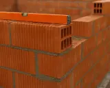 Nivel de burbuja sobre ladrillos huecos, mostrando la construcción de varios tipos de tabiques interiores.