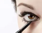 Ojo marrón recibiendo el toque final de maquillaje ojos negro con un lápiz.