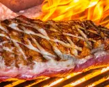 Jugosa viande de kobe a la parrilla, con marcas doradas y llamas naranjas danzando alrededor.