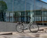 Elegancki, szary rower miejski z bagażnikiem i baterią, idealny do miasta.